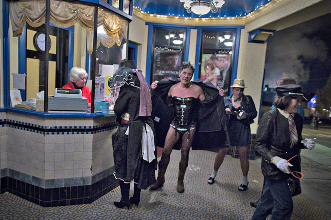 Cinema owner Ann Nelson sits in the ticket booth, as people in costume arrive to watch a late night screening of the 