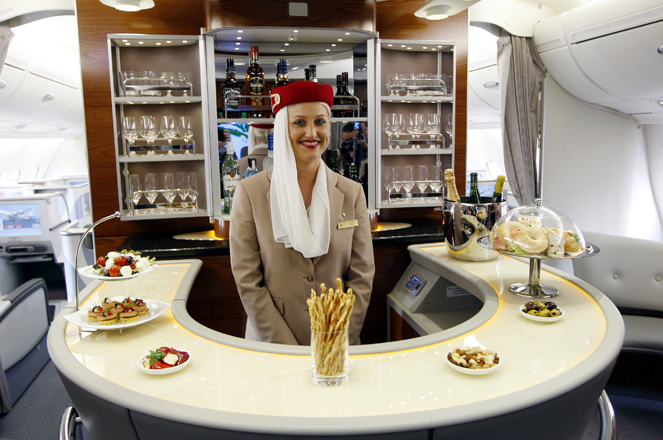 A flight attendant poses behind the bar in the rear of the business class section of Emirates' Airbus A380 after the jet arrived on its maiden flight at John F. Kennedy International Airport in New York August 1, 2008. Airbus's A380 superjumbo touched down in New York on Friday, marking the first commercial arrival of the giant, double-decker passenger plane on U.S. soil.  REUTERS/Chip East  (UNITED STATES)   FOR BEST QUALITY IMAGE: ALSO SEE GM1E57T038801 - RTR20JWF
