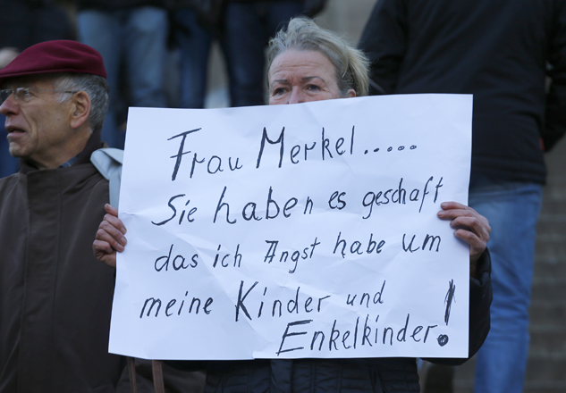 A woman holds up a placard reading 'Mrs Merkel you have achiedved that i'm afraid of the furture for my children and grandchildren' prior to a demonstration by anti-immigration right-wing movement PEGIDA (Patriotic Europeans Against the Islamisation of the West) in Cologne, Germany, January 9, 2016.  REUTERS/Wolfgang Rattay - RTX21MKQ