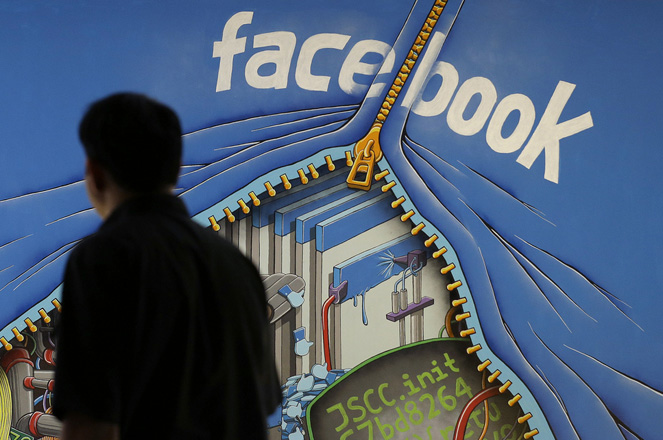 FILE - In this June 11, 2014, file photo, a man walks past a mural in an office on the Facebook campus in Menlo Park, Calif. On Thursday, May 12, 2016, Facebook pulled back the curtain on how its Trending Topics feature works, a reaction to a report that suggested Facebook downplays conservative news subjects. (AP Photo/Jeff Chiu, File)