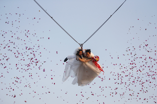 Bride Jintara Promchat, 28, and groom Kittinant Suwansiri, 29, fly while attached to cables during a wedding ceremony ahead of Valentine's Day at a resort in Ratchaburi province, Thailand, February 13, 2016. Four Thai couples took part in the wedding ceremony arranged by the resort. REUTERS/Athit Perawongmetha - RTX26Q9U
