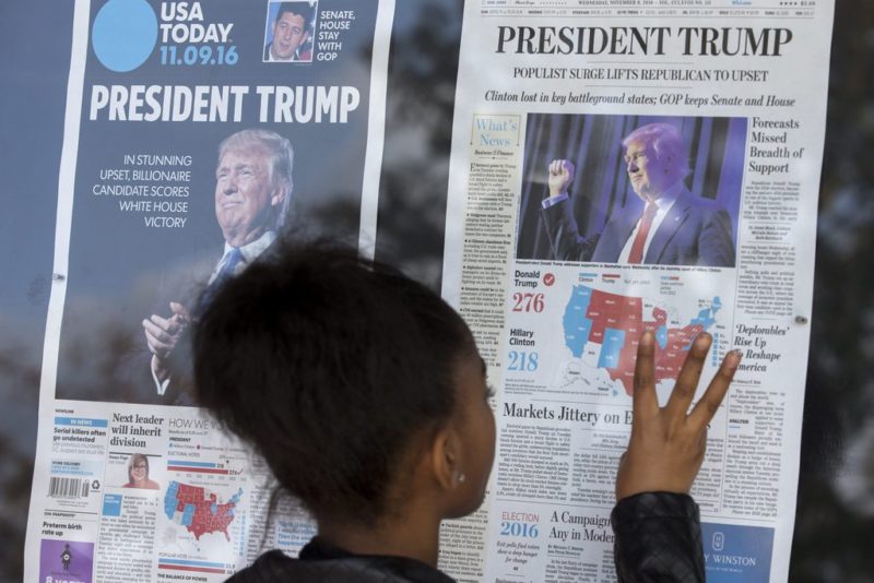 epa05624446 An African American child looks at election coverage on the front pages of today's newspapers on display outside the Newseum in Washington, DC, USA, 09 November 2016. The victory of Republican presidential candidate Donald Trump surprised many in the country after weeks of polling data appeared to indicate that Hillary Clinton was poised to win. EPA/MICHAEL REYNOLDS