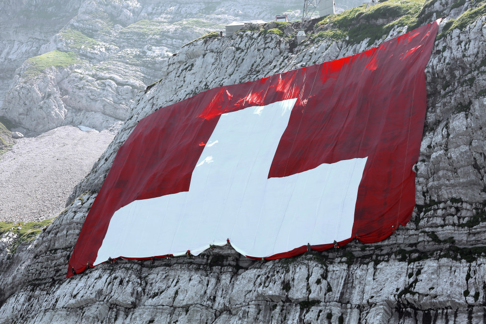 JAHRESRUECKBLICK 2015 - JULI - Workers furl up the world's largest Swiss flag at the ruggedly rock face of the mountain Saentis in Schwaegalp, eastern Switzerland, Friday, July 31, 2015. The flag measures 80 meters to 80 meters and is the world's largest Swiss flag. Saturday 1 August Switzerland is celebrating the national holiday. (KEYSTONE/Pascal Bloch)
