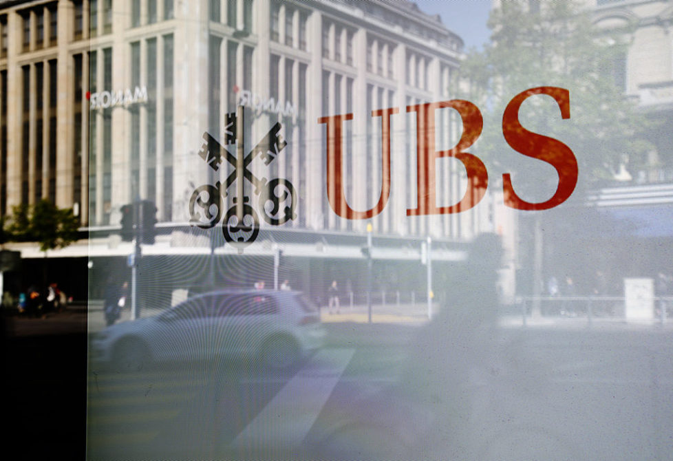 A UBS logo sits in the window of a UBS AG bank branch in Zurich, Switzerland, on Wednesday, April 16, 2014. Swiss and international regulators probably will ask banks to hold more capital in relation to total assets after the U.S. raised leverage-ratio requirements for the biggest lenders, UBS Chairman Axel Weber said. Photographer: Gianluca Colla/Bloomberg via Getty Images