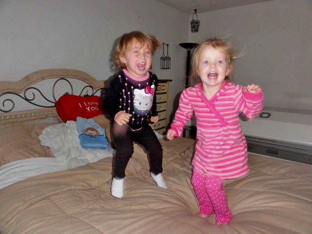 Zwei kleine Mädchen toben auf dem Bett herum. (Flickr/)