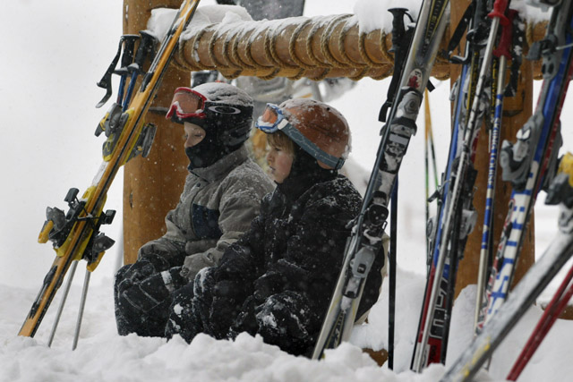 YOUNG KIDS SIT OUTSIDE LODGE DURING HEAVT SNOW AT SITE OF WORLD CUPMENS DOWNHILL.