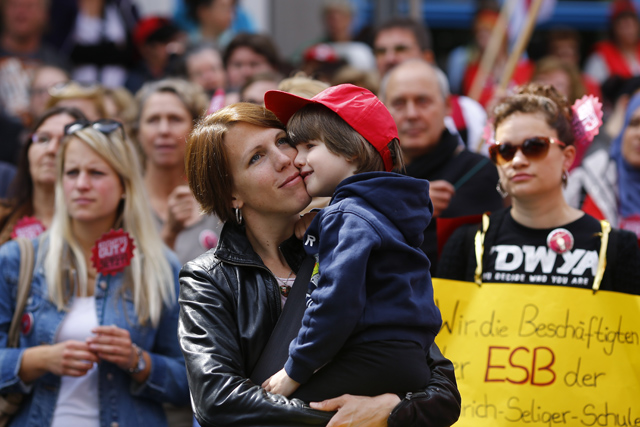 A nurse holds her son as she takes part in strike action in Frankfurt