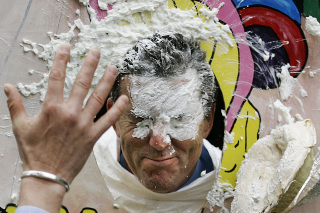 The Chairman of Pan American Silver Corporation Ross Beaty is hit in the face with a pie during fundraising for Sick Children's Hospital in Vancouver, British Columbia May 12, 2005. The pie throwing is part of the Mining for Charity Fair held annually in the city. REUTERS/Andy Clark AC - RTRAYUX