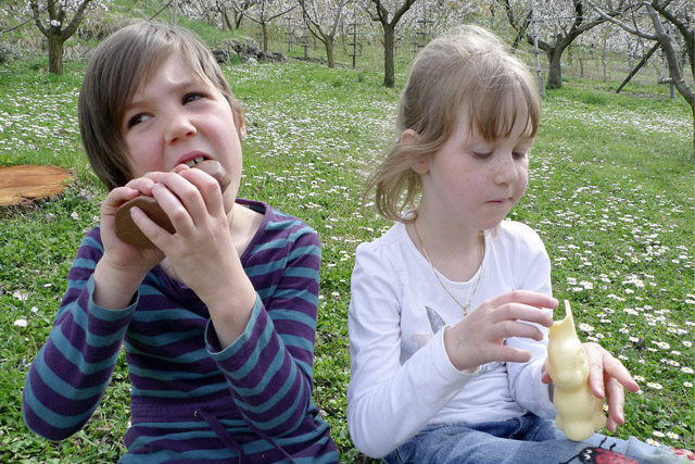 Les petite Fanny et Margot mangent les lapins de Paques trouves dans les pres le dimanche de 13 avril 2009 lors de Fetes de Paques a Salins en Valais. (KEYSTONE/Olivier Maire)