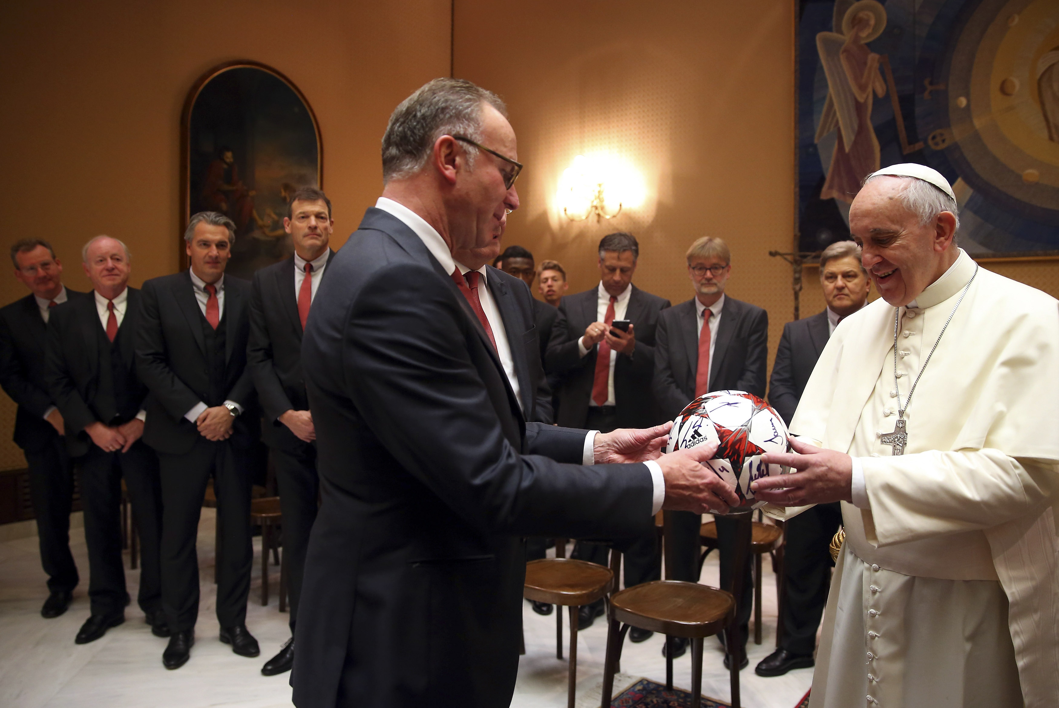 Pope Francis receives an autographed fottball from Bayern Munich's CEO Karlheinz Rummenigge during a private audience with the soccer team at the Palace of the Vatican in Vatican City, October 22, 2014. REUTERS/Alexander Hassenstein/Pool (VATICAN - Tags: SPORT SOCCER RELIGION) - RTR4B4TZ