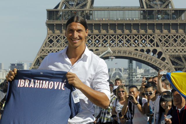 AC Milan striker Zlatan Ibrahimovic, of Sweden, pose in front of the Eiffel Tower with his jersey, in Paris, Wednesday, July 18, 2012 after signing an agreement with the Paris Saint Germain (PSG) club. Ibrahimovic will be the Ligue 1 club's third major signing of the summer, following the arrivals of former AC Milan teammate Thiago Silva and Napoli's Ezequiel Lavezzi. (AP Photo/Jacques Brinon)