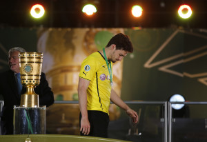 Borussia Dortmund's Mats Hummels (R) walks past the trophy next to German president Joachim Gauck after his team's German Cup (DFB Pokal) final soccer match against Bayern Munich in Berlin May 17, 2014. REUTERS/Ina Fassbender (GERMANY - Tags: SPORT SOCCER TPX IMAGES OF THE DAY) DFB RULES PROHIBIT USE IN MMS SERVICES VIA HANDHELD DEVICES UNTIL TWO HOURS AFTER A MATCH AND ANY USAGE ON INTERNET OR ONLINE MEDIA SIMULATING VIDEO FOOTAGE DURING THE MATCH. - RTR3PMT2