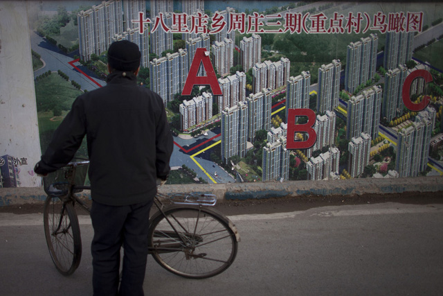 In this Jan. 17, 2013 photo, a man stops his bicycle to check an artistic rendering of a residential real estate project outside its construction site in Beijing, China, Thursday, Jan. 17, 2013.  China's economy rebounded in the final quarter of 2012 but optimism was tempered by warnings the shaky recovery could be vulnerable to a possible downturn in global trade. Economic growth rose to 7.9 percent in the three months ending in December as a recovery from China's deepest slowdown since the 2008 global crisis took hold, data showed Friday. (AP Photo/Alexander F. Yuan)