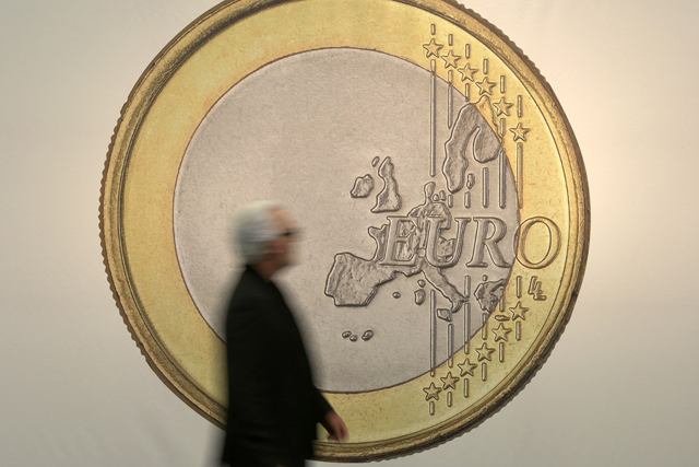 A man passes the artwork "Euro" by artist group Superflex at the art fair in Cologne, Germany, Thursday, April 16, 2015. (AP Photo/Martin Meissner)
