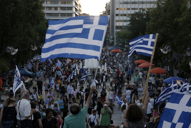 Supporters of the No vote wave Greek flags after the referendum's exit polls at Syntagma square in Athens, Sunday, July 5, 2015. Greece faced an uncharted future as officials counted the results of a referendum Sunday on whether to accept creditors' demands for more austerity in exchange for rescue loans, with three opinion polls showing a tight race with a narrow victory likely for the "no" side. (AP Photo/Petros Giannakouris)