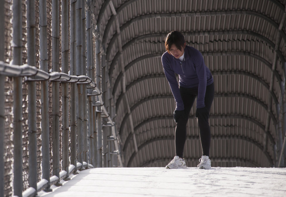 Sue Tran stretching before a snowy run in Salt Lake city, Utah.