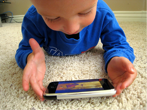 Der leuchtende Touchscreen zieht die Patschhändchen magisch an : Kleinkind mit iPhone.
