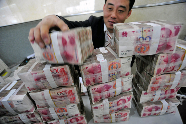 Ein Bankangestellter stapelt Renminbi-Noten. (Foto: Keystone)