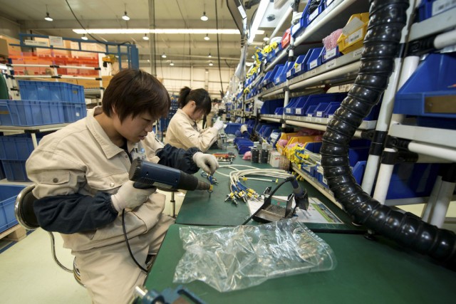 A woker assembles components at a workshop of Bernard Controls, a French business which manufatures electric actuators and controls for the automation of industrial valves and dampers, prior to a visit by France's President Francois Hollande, in Beijing on April 25, 2013. Hollande arrived in Beijing on a trip aimed at boosting exports to China, with hopes that deals can be reached over the sale of aircraft and nuclear power. AFP PHOTO / POOL / Ed Jones