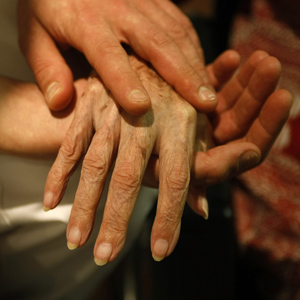 Eine Pflegerin hält die Hand einer alten Frau. (Keystone)