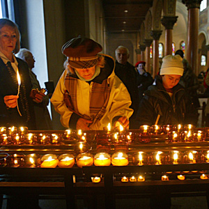 Gläubige zünden am Sonntag, 21. November 2004, nach dem katholischen Gottesdienst, in der Dreifaltigkeitskirche in Bern, Kerzen an. (Keystone/Monika Flückiger)