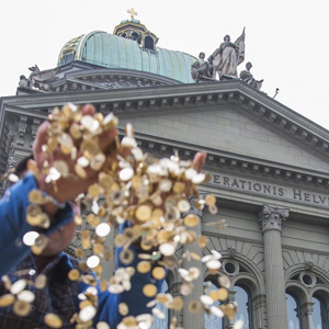 Ein Tourist spielt mit 5-Rappen-Münzen, die die Vertreter der Grundeinkommensinitiative vor dem Bundeshaus ausgelegt haben. (Keystone/Peter Klaunzer)