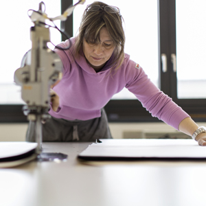 Eine Mitarbeiterin schneidet Stoff in der Zimmerli Textil AG in Mendrisio. Foto: Gaëtan Bally (Keystone)