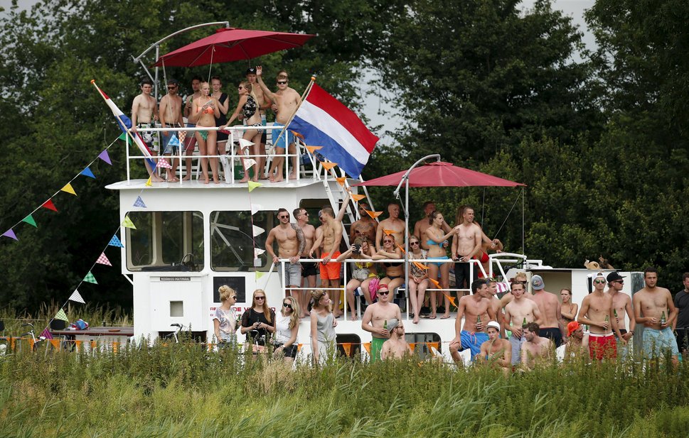 Spectators stand on a boat as they wait for the riders during the 166-km (103.15 miles) second stage of the 102nd Tour de France cycling race from Utrecht to Zeeland, July 5, 2015.  REUTERS/Benoit Tessier        TPX IMAGES OF THE DAY