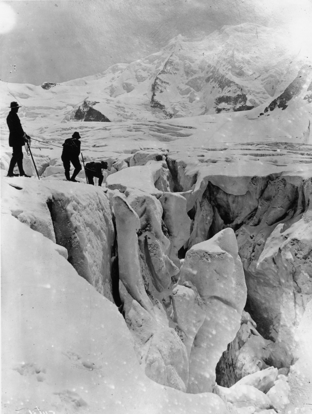 December 1910:  Three mountaineers crossing a crevsasse on the Pers Glacier in the Alps.  (Photo by Topical Press Agency/Getty Images)