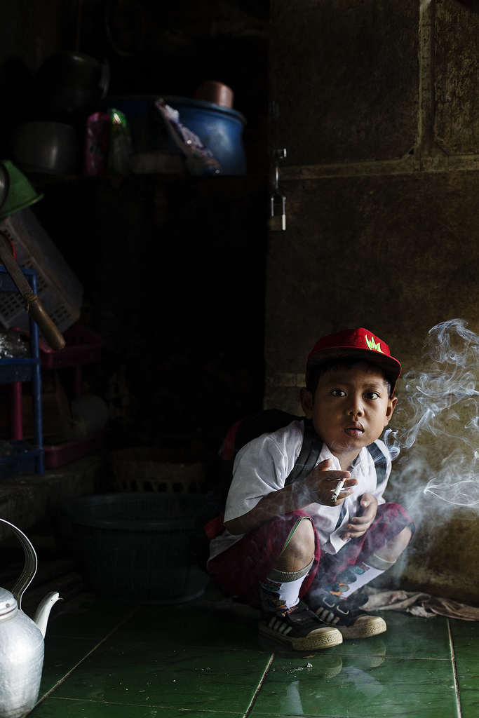Dihan Muhamad, who has smoked up to two packs of cigarettes a day before cutting down, poses for a photo as he has his first cigarette at 7AM at his home before he attends his first grade class on February 10, 2014. (Photo By: Michelle Siu)