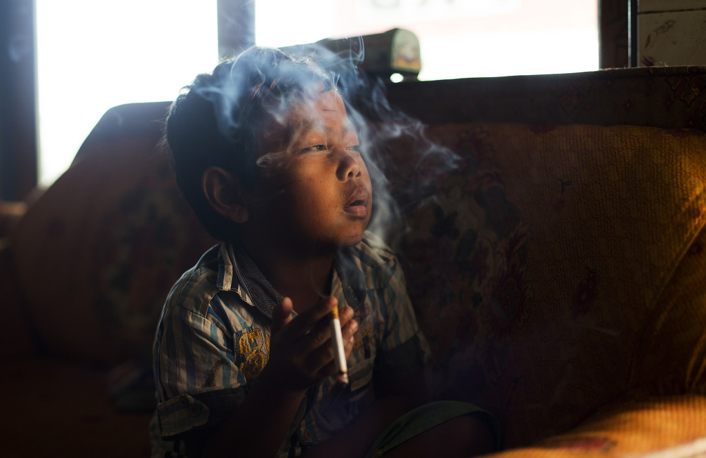 Dihan Muhamad, who used to smoke up to two packs of cigarettes a day before cutting down, poses for a photo as he smokes in his home on February 10, 2014. (Photo By: Michelle Siu)