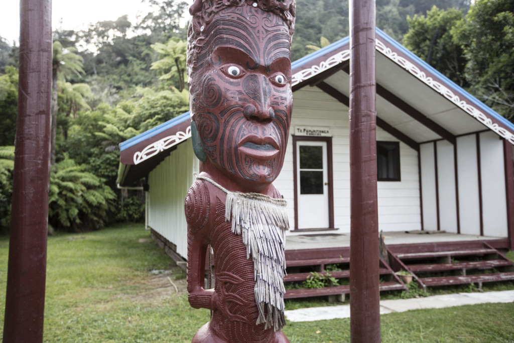 Tieke Kainga heisst der 3. Zeltplatz. Er befindet sich auf dem Gelände eines Maori Kultplatzes, genannt Marae. Der geschnitzte Pfahl (Pou Whenua) markiert die territorialen Ansprüche des Tieke Kainga Volkes. Kanu Trekking auf dem Whanganui River, Nordinsel, Neuseeland, Foto: Bernard van Dierendonck