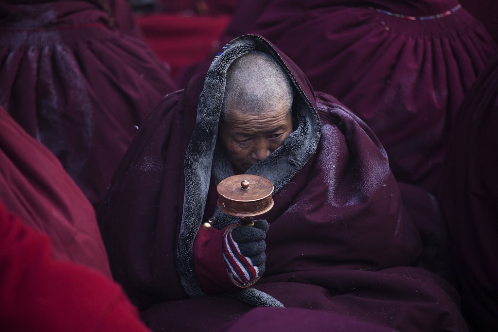 A Tibetan Buddhist nun spins a prayer wheel in sub zero temperatures at a Buddhist laymen lodge where thousands of people gather for daily chanting session during the Utmost Bliss Dharma Assembly, the last of the four Dharma assemblies at Larung Wuming Buddhist Institute in remote Sertar county, Garze Tibetan Autonomous Prefecture, Sichuan province, China November 1, 2015. The eight-day gathering of people chanting mantras and listening to teachings of monks starts every year around the 22nd of the ninth month on Tibetan calendar, the great day of Buddha's Descending from Tushita Heavens. The Larung Wuming Buddhist Institute, located some 3700 to 4000 metres above the sea level was founded in 1980 by Khenpo Jigme Phuntsok, an influential lama of Nyingma sect of Tibetan buddhism with only around 30 students but is now widely known as one of the biggest centres to study Tibetan Buddhism in the world. Picture taken November 1, 2015. REUTERS/Damir Sagolj