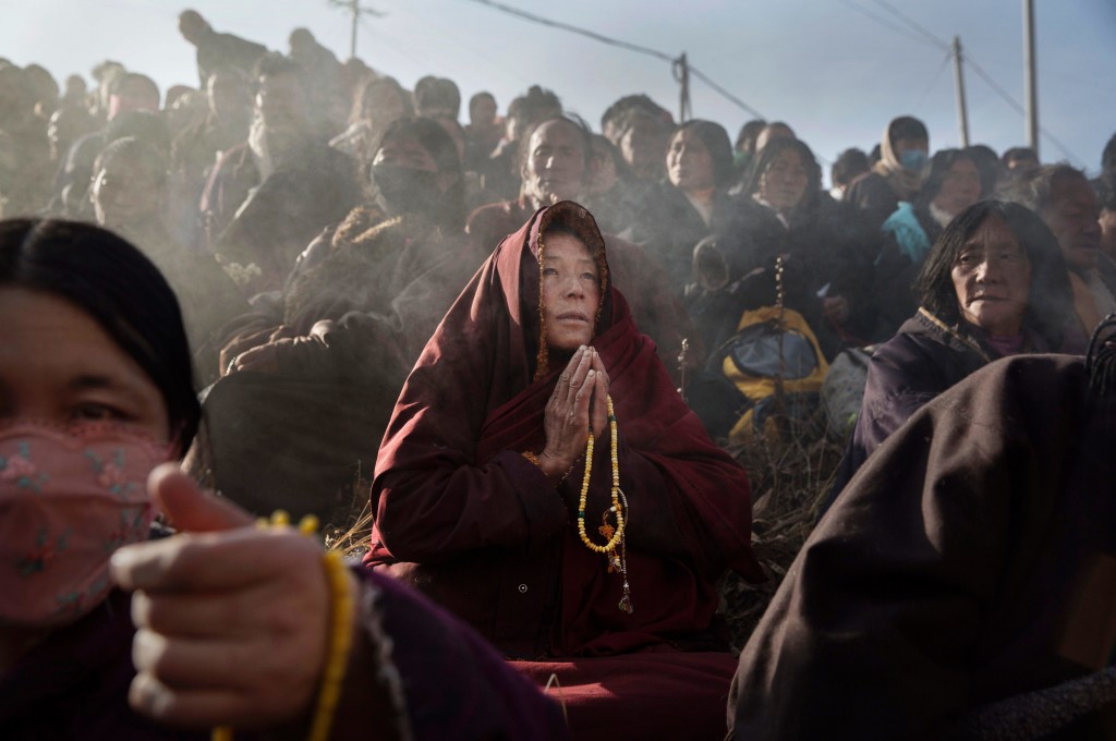 SERTAR, CHINA - OCTOBER 30: A Tibetan Buddhist monk prays with lay people on a hillside during a morning chanting session as part of the annual Bliss Dharma Assembly at the Larung Wuming Buddhist Institute on October 30, 2015 in Sertar county, in the remote Garze Tibetan Autonomous Prefecture, Sichuan province, China. The last of four annual assemblies, the week long annual gathering takes place in the ninth month of the Tibetan calendar and marks Buddha's descent from the heavens. Located high in the mountains of Sichuan, the Larung Wuming Buddhist Institute was founded in 1980 by an influential lama of the Nyingma sect and is widely regarded as the world's largest and most influential centres for Tibetan Buddhist studies. The school is home to thousands of monks and nuns and is popular for followers from all over the Tibetan areas and other parts of China. (Photo by Kevin Frayer/Getty Images)