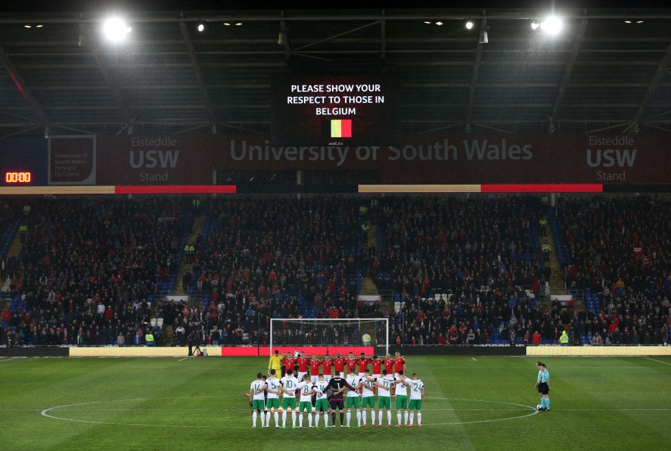 Wales' and the Northern Ireland, front, soccer teams, pose for a minutes silence in memory of the victims of the Belgium terror attacks as the stadium is lit in the colours of the Belgian flag prior to the International Friendly at the Cardiff City Stadium, Cardiff, Wales, Thursday March 24, 2016. (David Davies/PA via AP) UNITED KINGDOM OUT NO SALES NO ARCHIVE