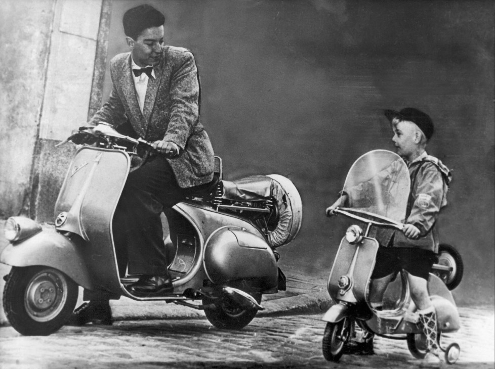 GERMANY - SEPTEMBER 02: A kid on a toy vespa scooter beside to a young man on vespa scooter motorcycle in 1953. (Photo by Keystone-France/Gamma-Keystone via Getty Images)