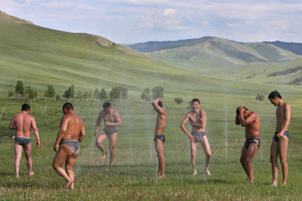 Mongolian wrestlers take an outdoor shower at the end of a train session at a camp in the grassland town of Suuj, about 60 km north of the capital Ulan Bator, July 5, 2006. Mongolians celebrate their annual festival of Naadam, a paegant of wrestling, hoseback-riding and archery, on July 11. This year's will be bigger than ever as Mongolians mark 800 years since Genghis Khan united the nation. REUTERS/Nir Elias (MONGOLIA) BEST QUALITY AVAILABLE Also see image: GM1DSZERTCAA - RTR1FIL4