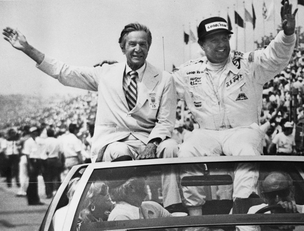 In a May 29, 1977, photo provided by Indianapolis Motor Speedway, Tony Hulman, left, and A.J. Foyt wave to fans during a victory lap after Foyt won his fourth Indianapolis 500 auto race in Indianapolis. (Indianapolis Motor Speedway via AP)