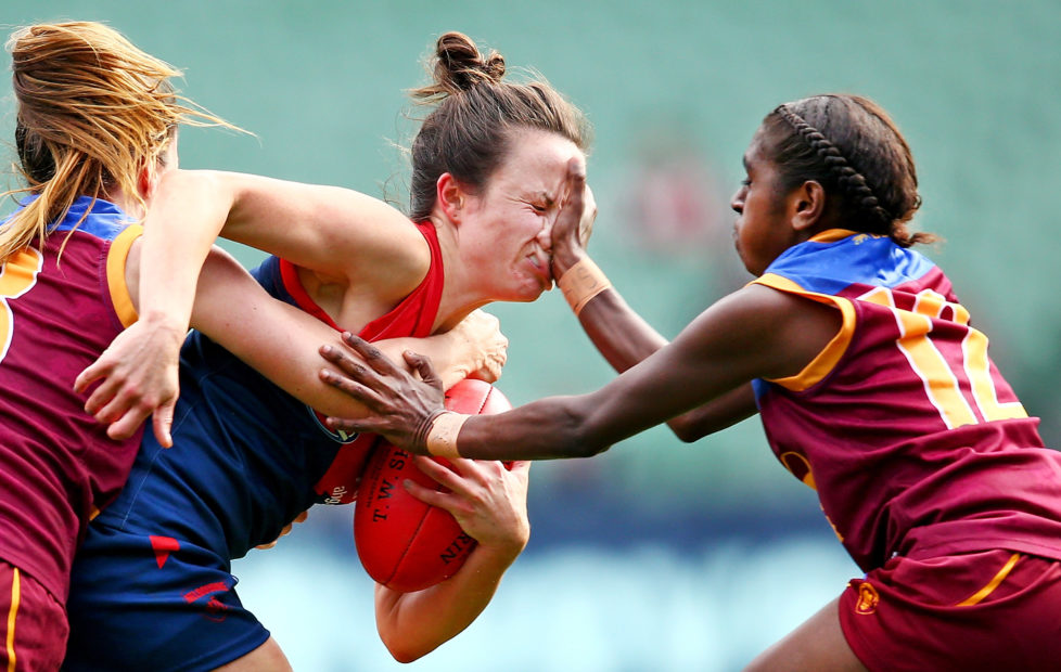 MELBOURNE, VICTORIA - MAY 22: Daisy Pearce of Melbourne is tackled by Emily Bates of Brisbane and Delma Gisu of Brisbane during the 2016 AFL Womens match between the Melbourne Demons and the Brisbane Lions at the Melbourne Cricket Ground on May 22, 2016 in Melbourne, Australia. (Photo by Scott Barbour/AFL Media/Getty Images)