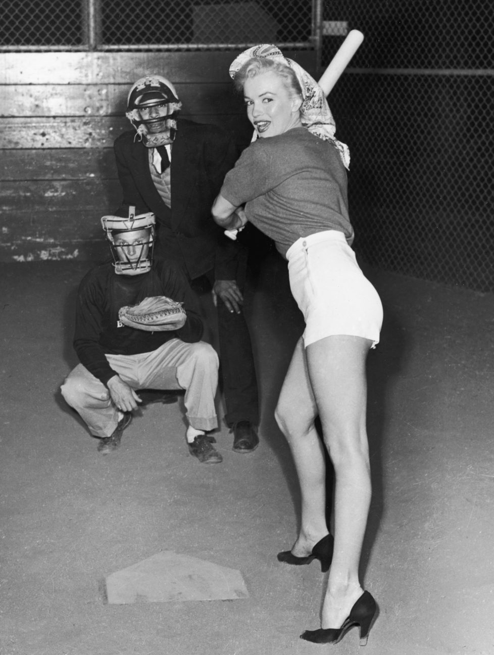 July 1952: American actor Marilyn Monroe (1926 - 1962), wearing shorts and high heels, prepares to swing a baseball bat during a 20th Century Fox Studio baseball league game. Studio employees play umpire and catcher. (Photo by Hulton Archive/Getty Images)