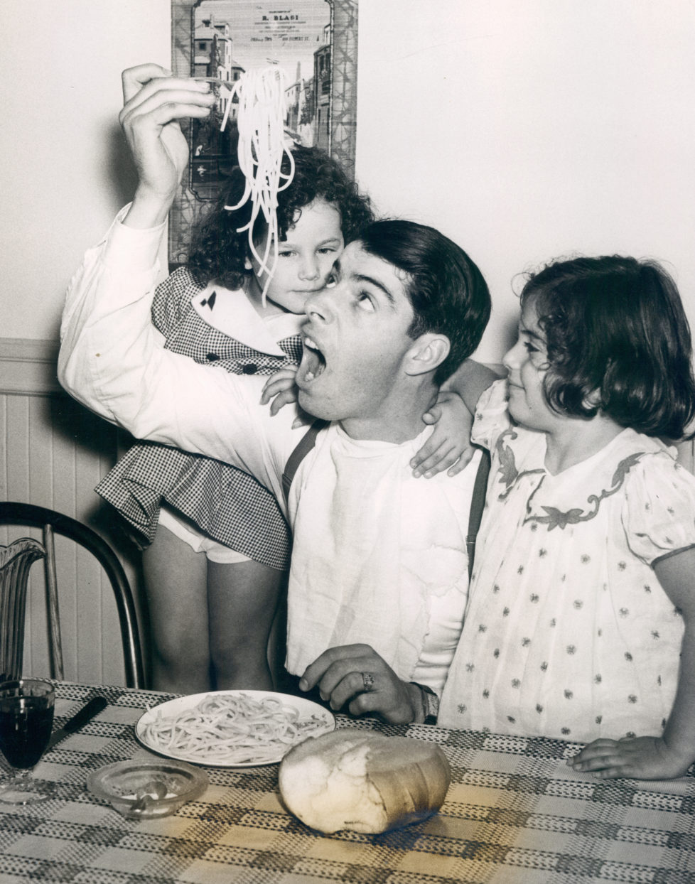 UNSPECIFIED - UNDATED: Joe DiMaggio eating pasta with a couple of young fans. (Photo by Sports Studio Photos/Getty Images)