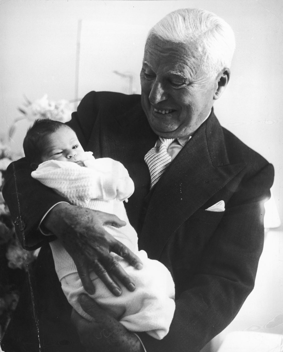 Comic actor Charlie Chaplin (1889 - 1977) holding his week-old son Christopher at the Mont-Choisi Clinic, Lausanne, Switzerland, 14th July 1962. Christopher is his eighth and last child with Oona O'Neill. (Photo by Daily Express/Archive Photos/Getty Images)