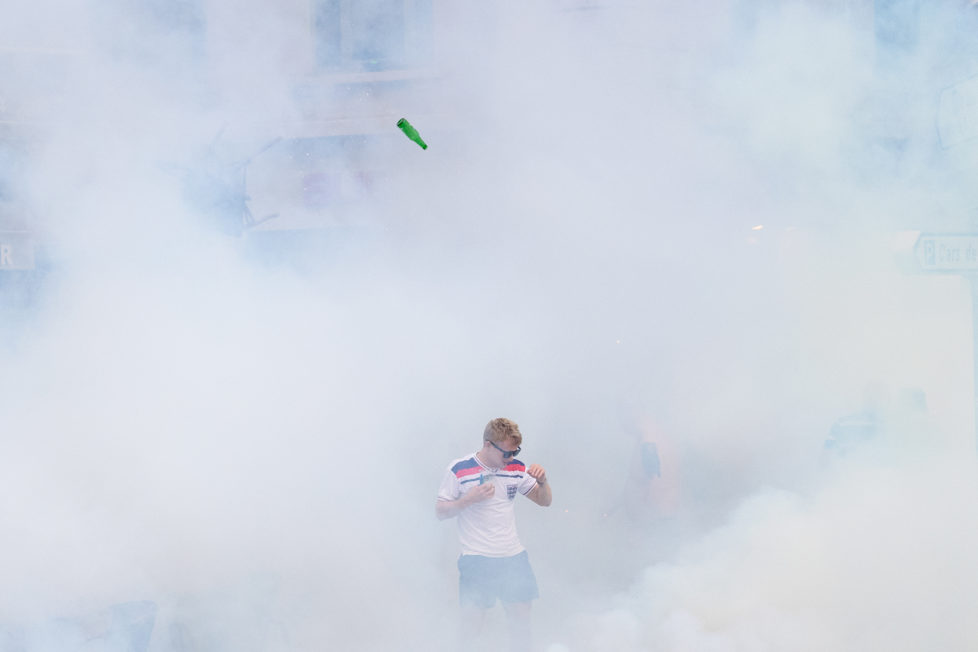An England supporter walks as he is engulfed in tear gas during clashes with police in Marseille, southern France, on June 10, 2016, on the eve of England's Euro 2016 football match against Russia. / AFP PHOTO / LEON NEAL