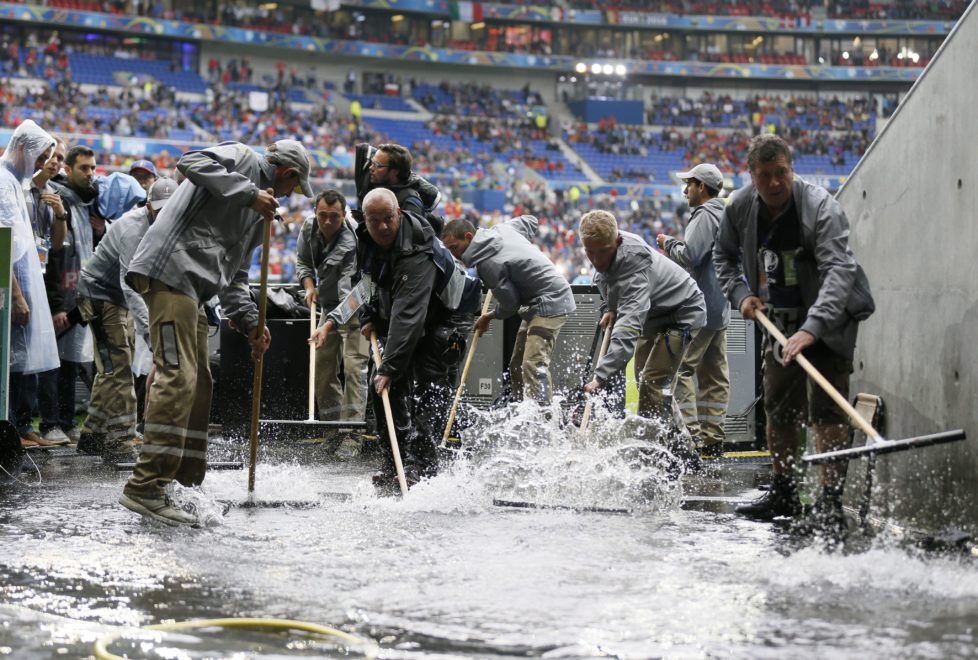epa05362518 Workers clear water away prior to the UEFA EURO 2016 group E preliminary round match between Belgium and Italy at Stade de Lyon in Lyon, France, 13 June 2016. (RESTRICTIONS APPLY: For editorial news reporting purposes only. Not used for commercial or marketing purposes without prior written approval of UEFA. Images must appear as still images and must not emulate match action video footage. Photographs published in online publications (whether via the Internet or otherwise) shall have an interval of at least 20 seconds between the posting.) EPA/SERGEY DOLZHENKO EDITORIAL USE ONLY