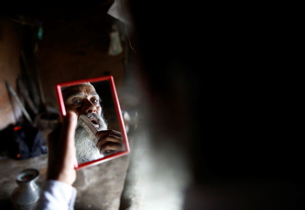 Durga Kami, 68, who is currently studying tenth grade at Shree Kala Bhairab Higher Secondary School, looks into a mirror as he combs his beard while getting ready for school in Syangja, Nepal, June 5, 2016. Kami has promised his classmate Sagar Thapa that he will cut his beard off if he passes tenth grade. REUTERS/Navesh Chitrakar. SEARCH "DURGA KAMI" FOR THIS STORY. SEARCH "THE WIDER IMAGE" FOR ALL STORIES