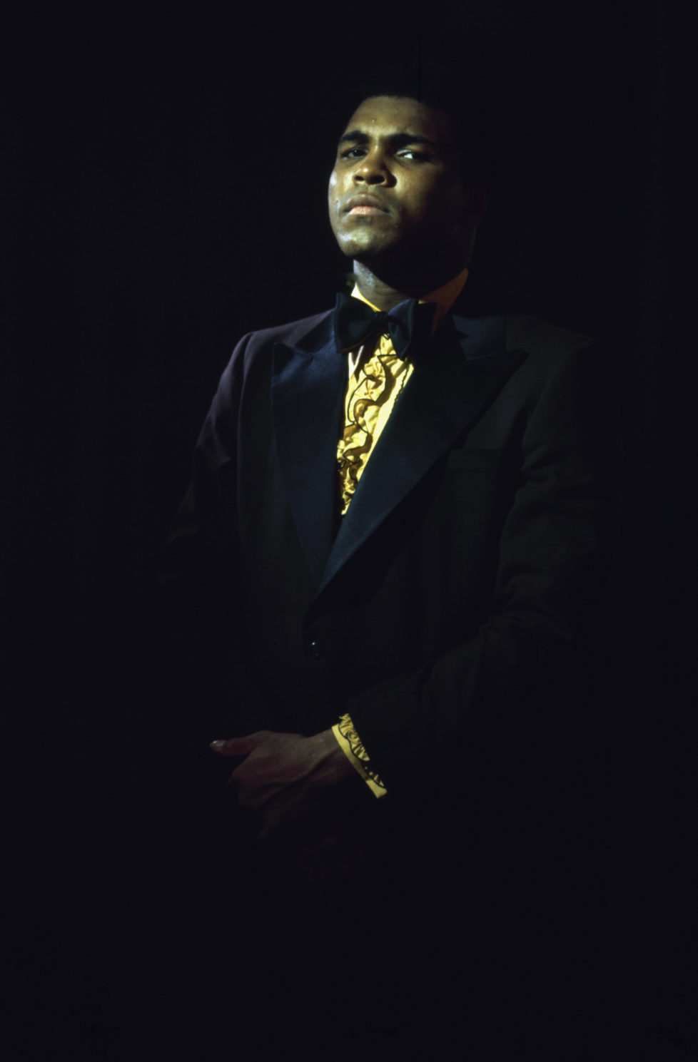 Portrait of American heavyweight boxer Muhammad Ali, in a tuxedo, ruffled yellow shirt, and bowtie, 1971. The portrait was taken prior to his first bout with Joe Frazier, where he unsuccessfully battled for the title belt on March 8, 1971 at Madison Square Garden. (Photo by John Shearer/The LIFE Picture Collection/Getty Images)
