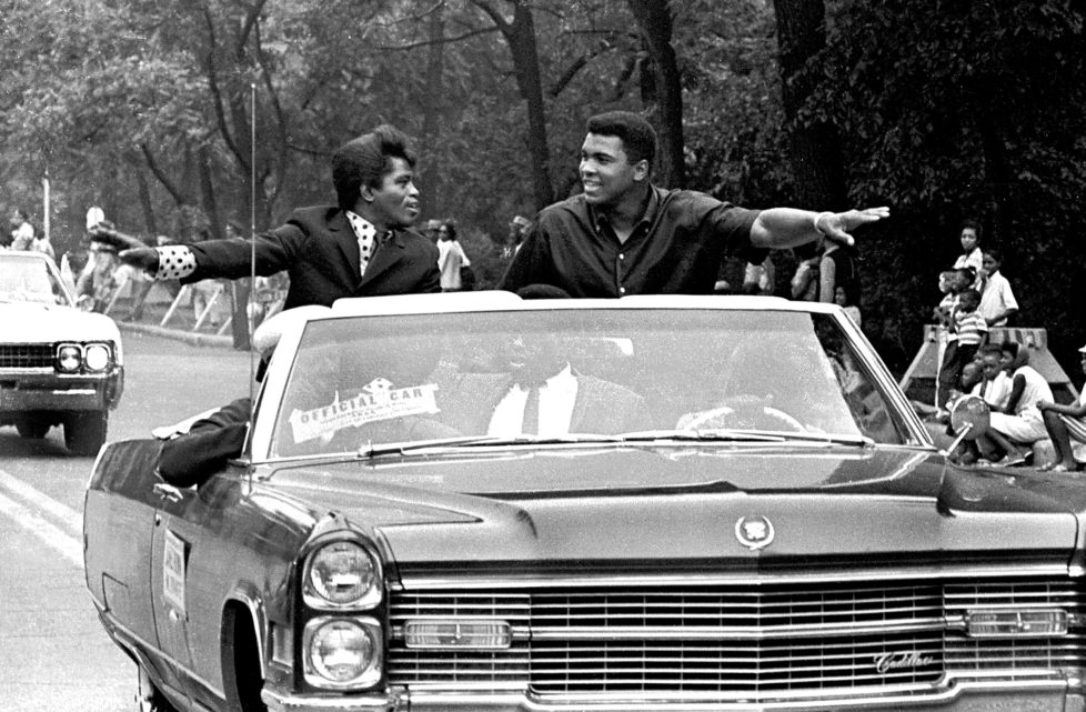 American singer James Brown (1933 - 2006) and boxing champ Muhammad Ali (then known as Cassius Clay), smile and greet parade goers while participating in the annual Bud Billiken parade, Chicago, Illinois, August 1966. (Photo by Robert Abbott Sengstacke/Getty Images)