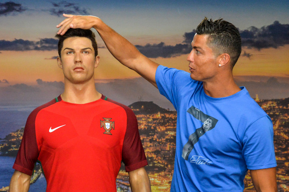 Portugese forward Cristiano Ronaldo poses next to a wax statue representing himself during a visit to the new location of the CR7 museum dedicated his professional career at Funchal, on the Portuguese island of Madeira on July 23, 2016. / AFP PHOTO / JOANA SOUSA