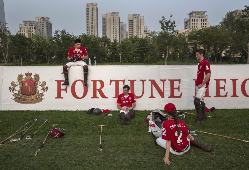 TIANJIN, CHINA - JULY 17: Players from the Cornell University Polo team rest during a break in a match during the intervarsity tounrament at the Tianjin Goldin Metropolitan Polo Club on July 17, 2016 in Tianjin, China. China's rising affluence has nurtured growing interest in polo and other past-times regarded as noble or prestigious by the country's elite. Clubs and international-size polo fields have been built in various cities including Beijing and Shanghai, and on the outskirts of Tianjin, where membership at the exclusive Goldin Metropolitan, China's largest polo club, is by invitation-only and fees can be significant for polo team owners. Increasingly, wealthy Chinese parents are choosing polo and other equestrian activities for their children as a way to bolster their credentials for admission to top-tier universities in the United States and the United Kingdom. While the so-called "sport of kings" became a mainstay in Hong Kong during the era of British rule, polo is a relatively new sport to mainland China. Professional polo players are frequently flown in from countries such as New Zealand and Argentina in order to field competitive matches. Many of the polo clubs in China are tied to luxury real estate developments. (Photo by Kevin Frayer/Getty Images)