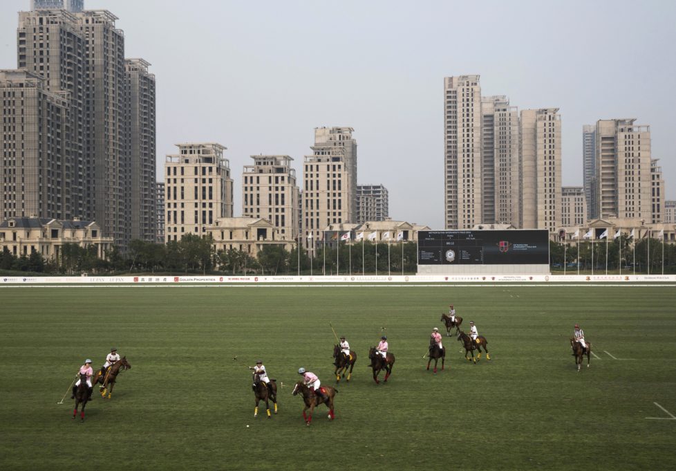 TIANJIN, CHINA - JULY 17: Chinese players from the Metropolitan Polo Club team, in white, and players from the United States and Great Britain play an exhibiton match at the Tianjin Goldin Metropolitan Polo Club on July 17, 2016 in Tianjin, China. China's rising affluence has nurtured growing interest in polo and other past-times regarded as noble or prestigious by the country's elite. Clubs and international-size polo fields have been built in various cities including Beijing and Shanghai, and on the outskirts of Tianjin, where membership at the exclusive Goldin Metropolitan, China's largest polo club, is by invitation-only and fees can be significant for polo team owners. Increasingly, wealthy Chinese parents are choosing polo and other equestrian activities for their children as a way to bolster their credentials for admission to top-tier universities in the United States and the United Kingdom. While the so-called "sport of kings" became a mainstay in Hong Kong during the era of British rule, polo is a relatively new sport to mainland China. Professional polo players are frequently flown in from countries such as New Zealand and Argentina in order to field competitive matches. Many of the polo clubs in China are tied to luxury real estate developments. (Photo by Kevin Frayer/Getty Images)